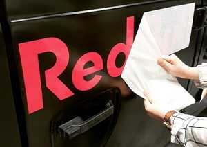 Expertly peeling back the vinyl backing sheet for a gloss finish vehicle graphic installation