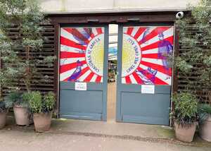 Entrance at Groves Nurseries with colorful circus-themed artwork and plants in pots beside the door.
