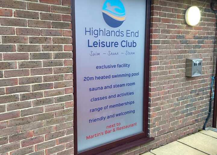 Sign for Highlands End Leisure Club on a brick wall.