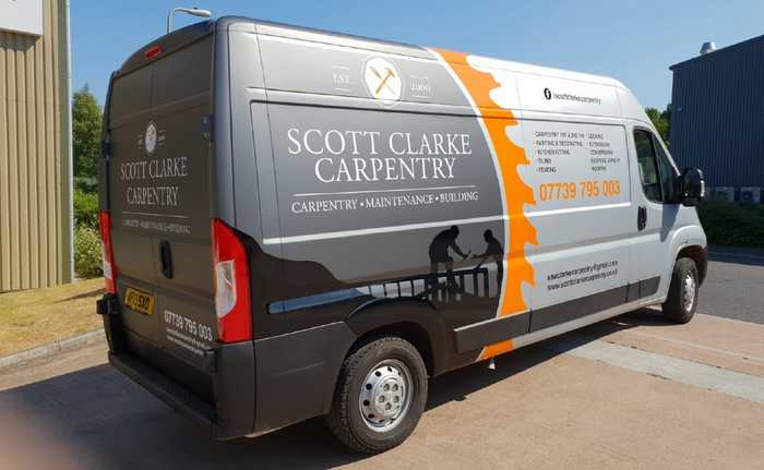 A grey van signwritten with business graphics and text
