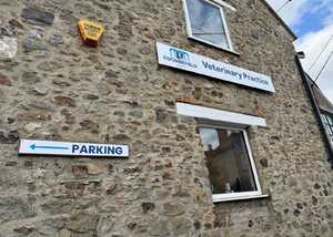 Stone building with a sign for "Veterinary Practice" and an arrow pointing left for parking.