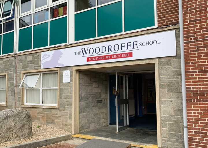 Entrance of The Woodroffe School with a sign and large windows above.