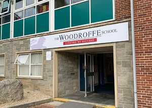 Entrance of The Woodroffe School with a sign and large windows above.