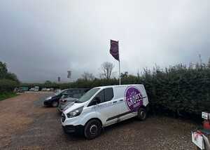 Van parked at a nursery with flags and a cloudy sky in the background.