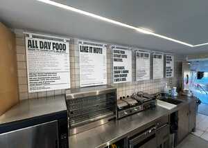 Bakery interior with food menus on the wall and stainless steel equipment visible.