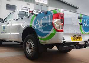 A truck, half vinyl-wrapped with business logo