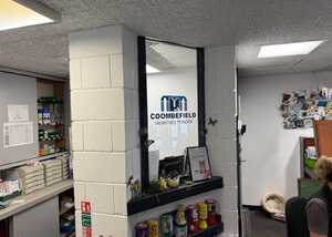 Interior of an office with a logo on a window and shelves with various items.