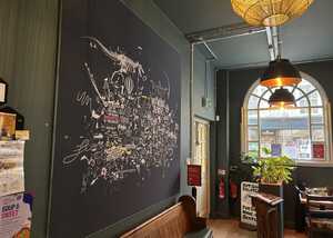 Interior of a cafe with a large mural, a window, and a hanging light fixture.