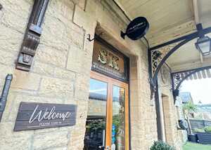 Entrance of a stone building with a "Welcome" sign and a circular sign above.
