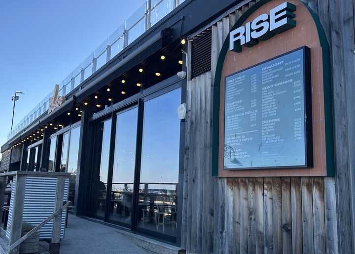 Exterior of Rise Bakery with a wooden facade and menu displayed.