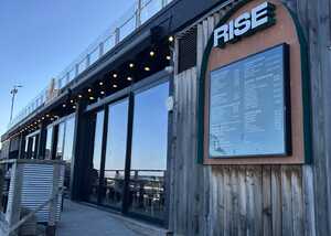 Exterior of Rise Bakery with a wooden facade and menu displayed.