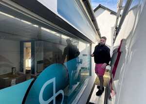 A person stands between two buildings, one with a large blue Sonder logo, under a clear sky.