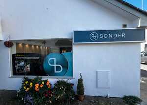 Storefront with "Sonder" sign and colorful flower display outside.