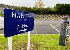 Sign for Nantes Solicitors with an arrow indicating parking direction.