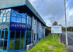 Building exterior with "Nantes Solutions" sign and "Poundbury House" directional sign.