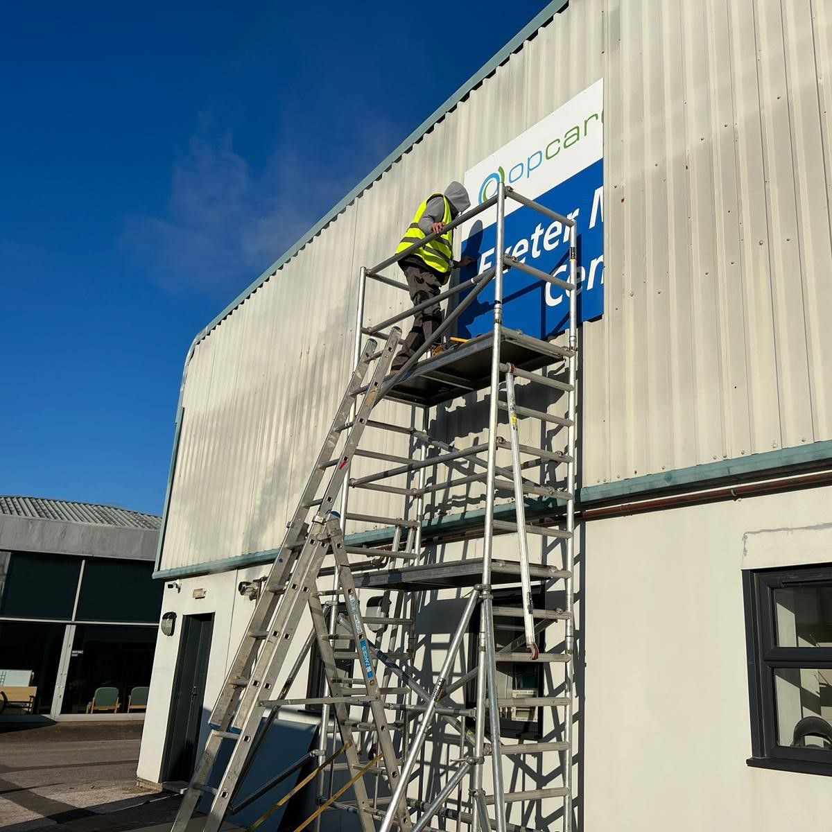 Installing Large Printed Aluminium Sign Panel for Exeter Mobility Centre. Installed in 4 sections..jpg