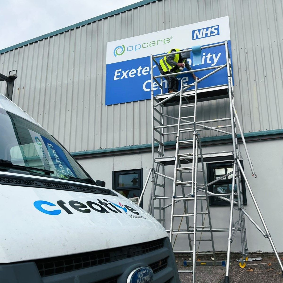 Installing Large Printed Aluminium Sign Panel on Scaffolding for Exeter Mobility Centre.jpg
