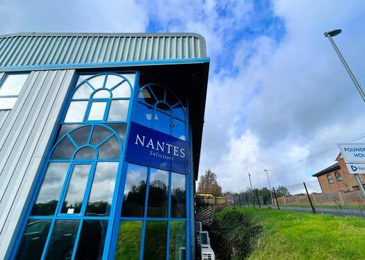 Building with blue accents and a sign reading "NANTES" against a cloudy sky.