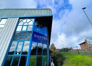 Building with blue accents and a sign reading "NANTES" against a cloudy sky.