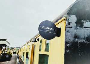 Sign on a train car displaying "PLATFORM EST 2015." Cloudy sky in background.