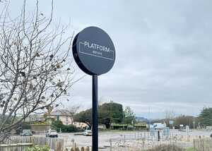 Sign for "PLATFORM" on a post in an empty parking lot under a cloudy sky.